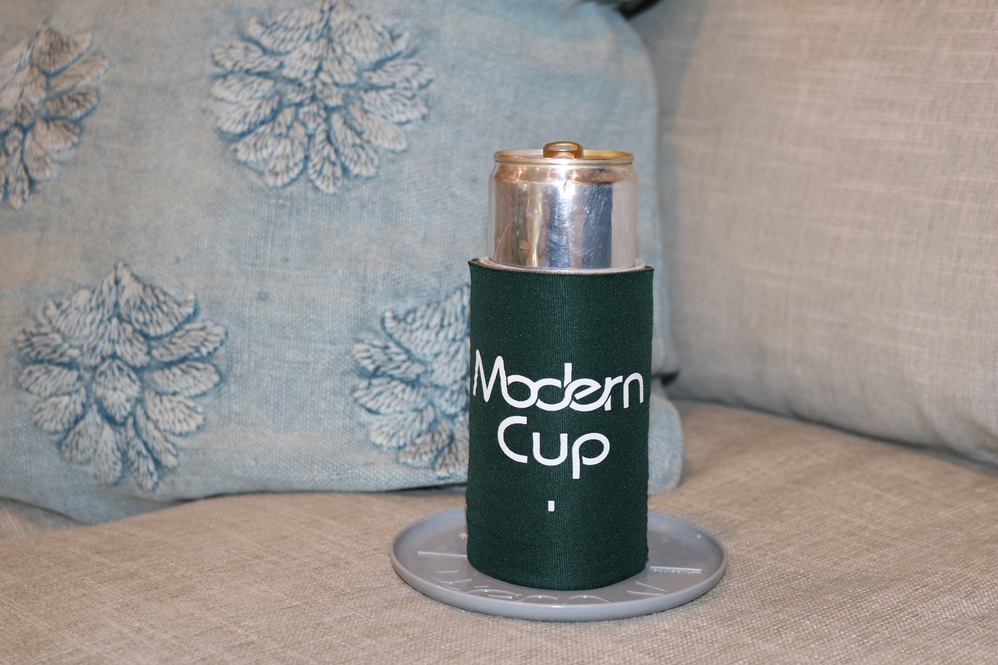 A dark green koozie labeled "Modern Cup"